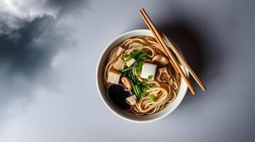 Noodles with tofu and vegetables in a bowl on a cloudy background photo