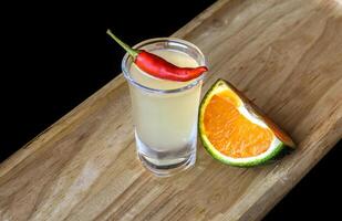 Alcohol shot made of orange juice and chili on the wooden board with with copy space photo