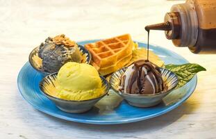 Homemade ice cream with waffle on plate with chocolate syrup photo