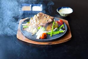 Roasted fire beefsteak with vegetables and greens on plate isolated on black background side view photo