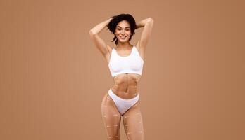 A woman stands confidently, showcasing her curves while practicing body sculpting and contouring techniques. photo