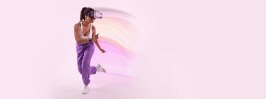 Experiencing the metaverse. Active african american lady gaming with virtual reality goggles over pink background, free space. Young woman enjoying 3D experience in studio photo