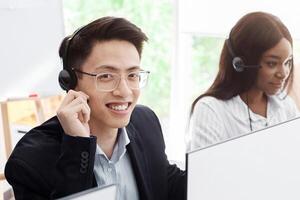 Customer support phone operators in headsets behind computer monitors at call center, blank space photo
