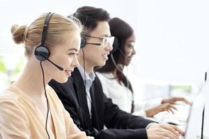 Team of hotline operators with headsets communicating to clients at modern call center, free space. Technical support managers working with computers at open space office photo