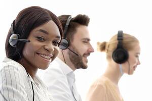 Telecommunications concept. Positive helpdesk operators selling services or goods through VoIP telephony at modern call centre. Diverse team of tech support managers talking to clients at office photo