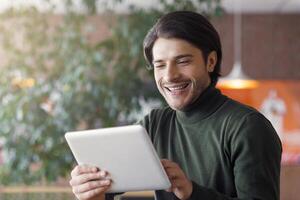 Application for business. Joyful businessman using digital tablet at modern cafe, drinking coffee, empty space photo