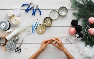 Creative diy hobby. Handmade tools for making christmas present, box in craft paper with red ribbon. Top view of white wooden table with copy space on sheet of paper, decoration of gift. photo
