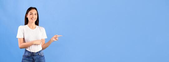 Look There. Smiling girl pointing her fingers at copyspace over turquoise studio background, banner photo