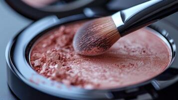 A close up view of a makeup brush picking up blush powder from a compact on a surface, showcasing the application process in a personal care environment. photo