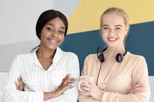 Portrait of female call centre operators smiling and looking at camera during their coffee break at modern office, free space. Positive customer support agents posing at workplace photo