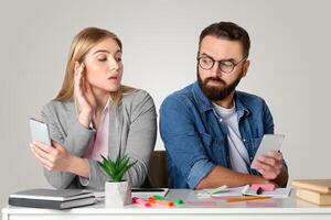 A man and woman sit at a table, engaged in a heated conversation about their relationship. Both are holding phones, signaling a communication breakdown, highlighting domestic issues. photo