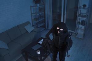 Robbery Concept. The surveillance camera captured as a masked thief breaks the apartment and looking up photo