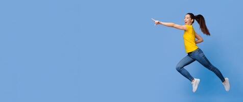 Look there. Excited Asian Girl Jumping And Pointing Aside At Copy Space On Purple Background, Full-Lenght Shot, Panorama photo