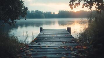 A tranquil wooden dock stretches into a foggy lake at sunrise, offering a sense of stillness and the promise of a new day amidst the quiet beauty of nature. photo
