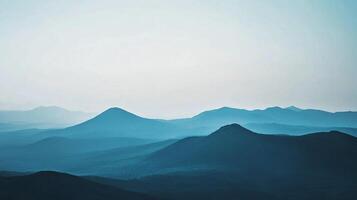 A serene view of layered blue mountains in soft morning light, creating a peaceful and tranquil atmosphere ideal for outdoor enthusiasts and nature lovers. photo
