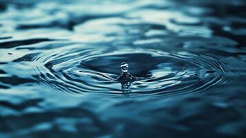 A solitary drop of water gracefully falls into a tranquil surface, creating ripples that symbolize serenity and depth in a calming visual display. photo
