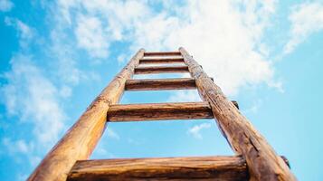 Wooden ladder reaching up into a bright blue sky, symbolizing ambition, aspiration, and the path towards achieving goals. photo