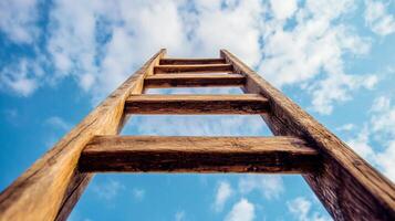 Ladder reaching for the bright blue sky with fluffy white clouds, symbolizing ambition, growth and ascension towards brighter future. photo
