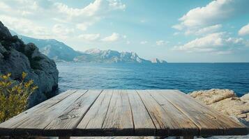 Scenic coastal view with a wooden table foreground, mountains in the distance, and calming blue waters stretching to the horizon. photo