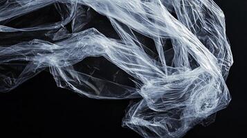 Plastic film against a black background, reflecting light and creating interesting textures. Emphasizing the fragility and impermanence. photo