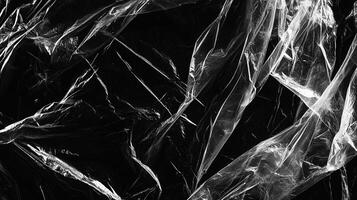 Monochrome abstract of clear crumpled material against a dark background, creating intricate folds and light reflections. photo