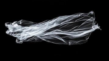 Translucent plastic sheet floats against a dark void, forming elegant curves in light and shadow. Emptiness surrounds delicate form. photo