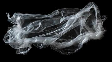 A translucent and crinkled material floats in darkness, like an ethereal veil, with its folds and shadows adding depth to the scene. photo