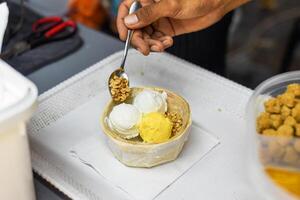 Hand hold coconut and mango ice cream in coconut shell in Jalan Alor street food market in Kuala Lumpur photo