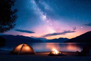 Illuminated tent and campfire under the milky way on a lake shore at sunset photo