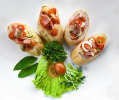 Bruschetta with tomatoes ham,onion and olive oil on white plate close up photo