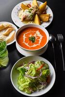 Lunch set made of tomato cream soup salad chicken with potato, lemonade on black photo