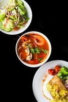 Lunch set made of tom yum soup, salad, grilled basa fish, rice, on black background photo