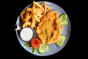 Chicken chop steak with vegetables on a blue plate isolated on black background side view photo