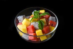 Fruit salad made of east asian fruits isolated on a black background side view photo