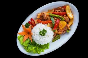 Stewed pork with vegetables and rice isolated on black background top view photo