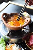 Traditional korean hot pot dish with beef and spicy bouillonn on black table photo
