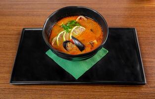 Soup tom yum with seashells and mussels on wooden table photo