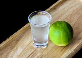Alcohol shot made of lime juice on a wooden board with with copy space photo