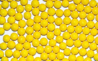 Many yellow round dragees of ascorbic acid vitamin C isolated on a white background photo