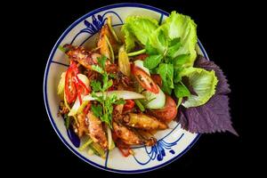 Fried squid with vegetables on a black background for a menu photo