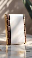 Elegant chocolate bar with a sleek white label and shimmering gold wrapper, set against a luxurious marble backdrop, a sweet indulgence. photo