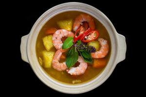 Stew with shrimps and pineapple isolated on black background top view photo
