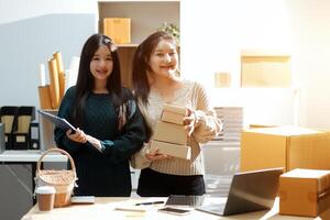 Two women standing in front of boxes and a laptop photo