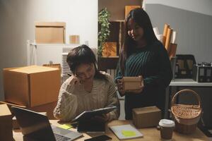 Two women working in an office with boxes and papers photo
