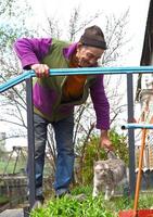 Old Russian man touching a cat and laughing photo