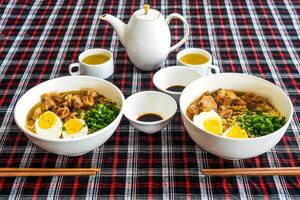 Japanese ramen with chicken and soy sauce on the table with teapot and green tea photo