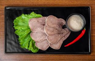 Appetizer with slices of tender beef on a black plate on a white background photo