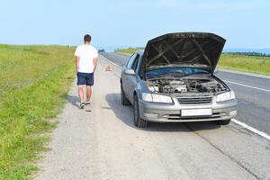 Sad man near broken car searching help in field photo