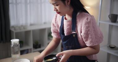 Handheld high angle view shot, Beautiful woman is preparing the process of coating chicken with all the ingredients in a bowl before frying the chicken on a pan. Cooking concept video