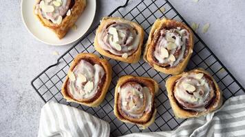Delicious cinnamon rolls with icing and almond flakes on the rack video